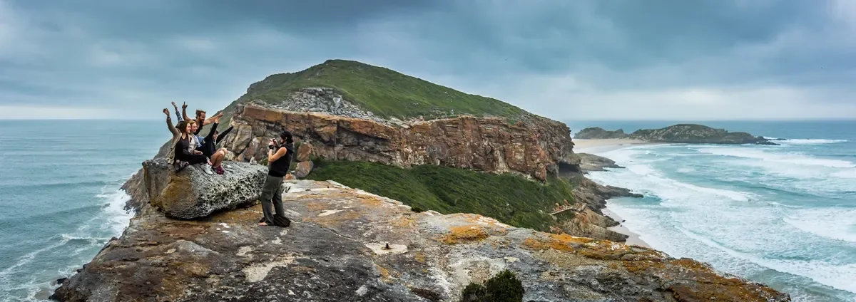 Hikers pausing at a Robberg Nature Reserve viewpoint above the peninsula and beach near Plettenberg Bay, Garden Route, South Africa