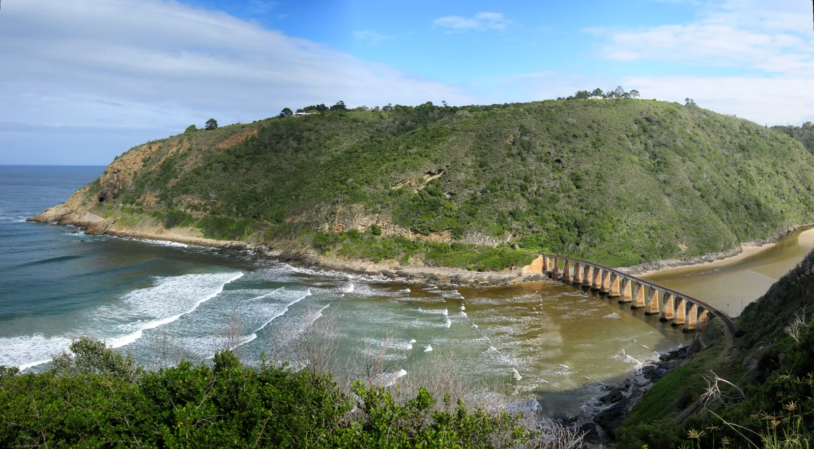 Kaaimans River viaduct at Wilderness where river meets sea, old railway bridge curves through indigenous forest, Garden Route
