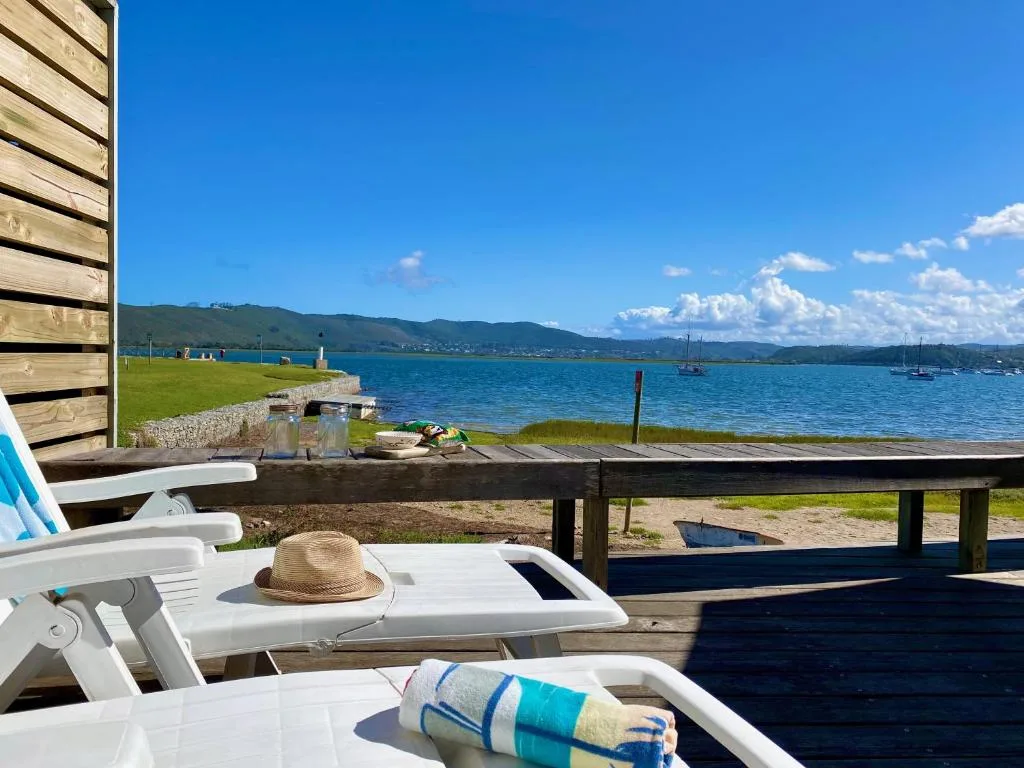 TH39 Thesen Islands — lagoon-edge deck with loungers and a sailboat moored at the private jetty, Knysna