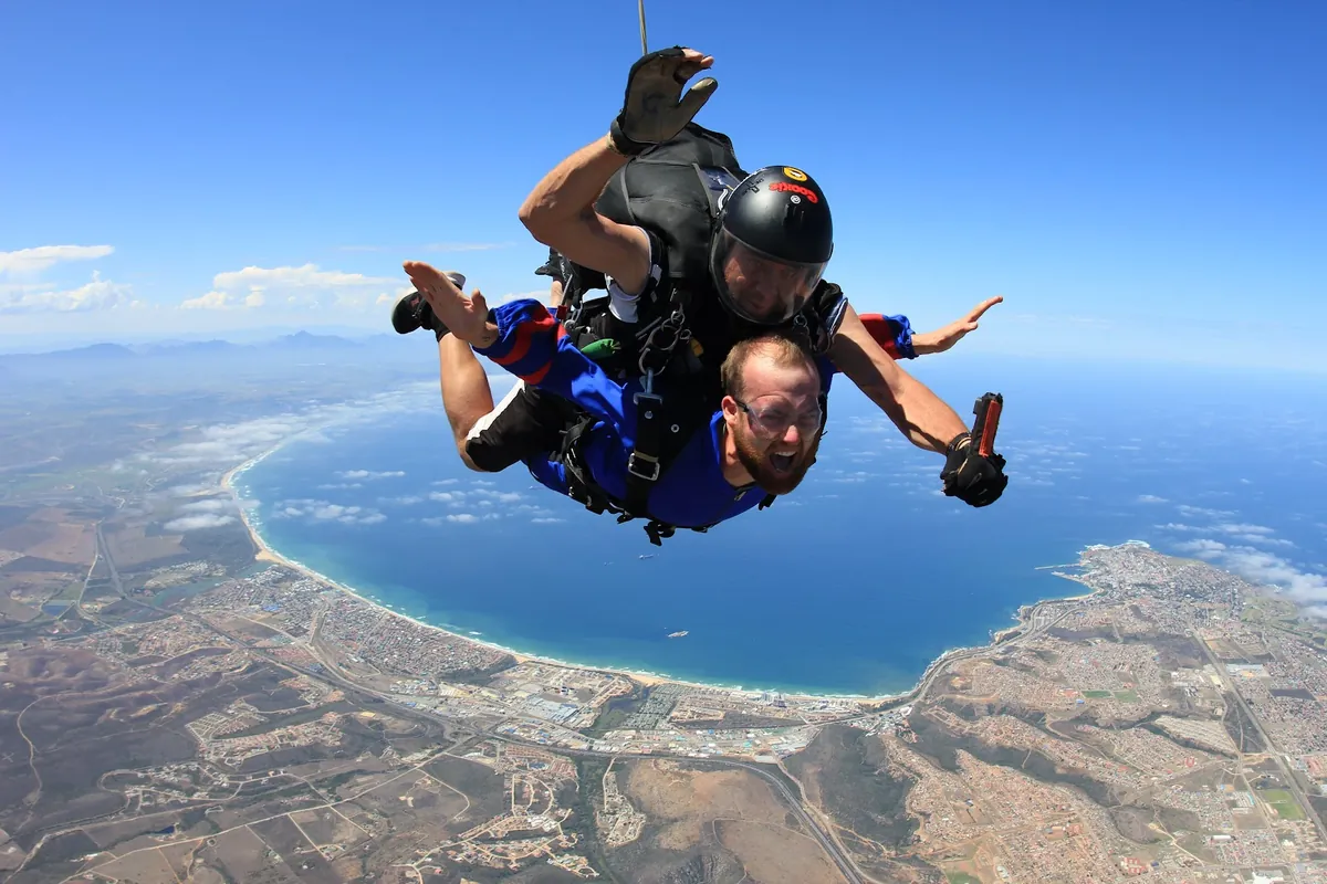 Tandem skydiver in freefall high above the Mossel Bay coastline and the curve of the bay
