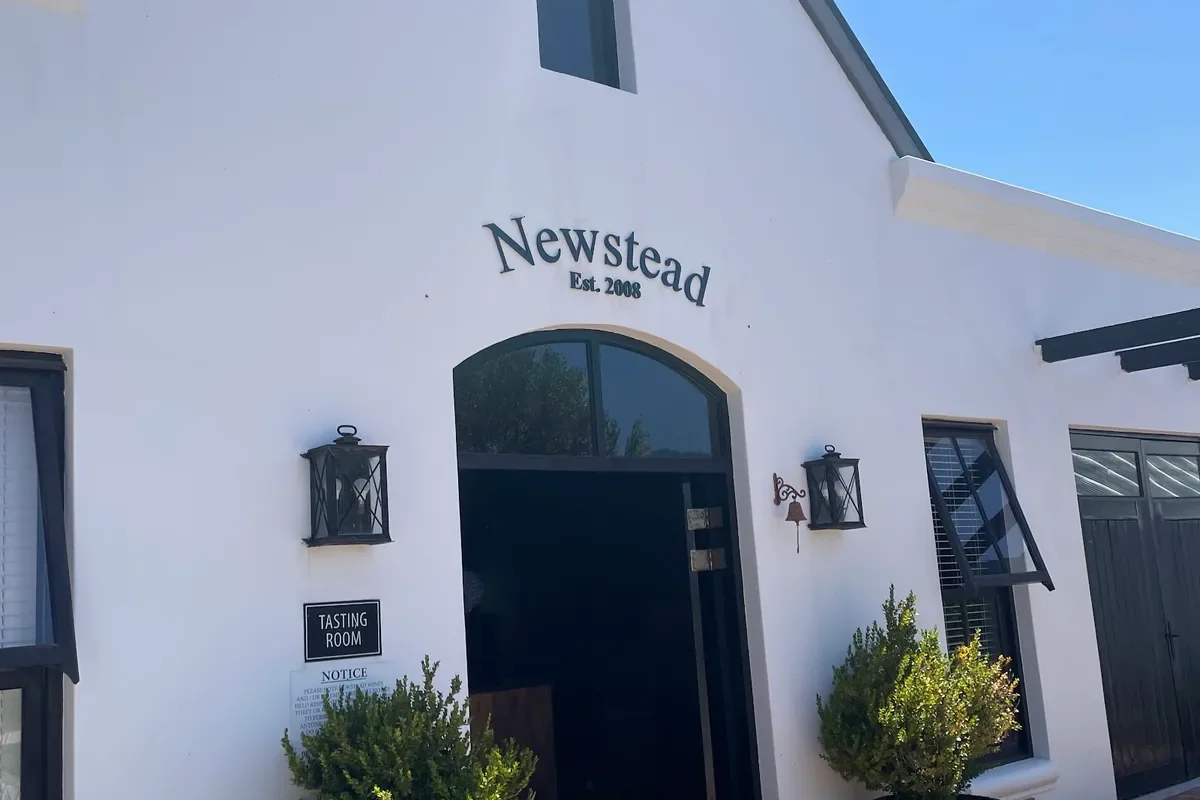The white gabled tasting room entrance at Newstead Wine Estate, lettered Newstead Est. 2008 above an arched doorway